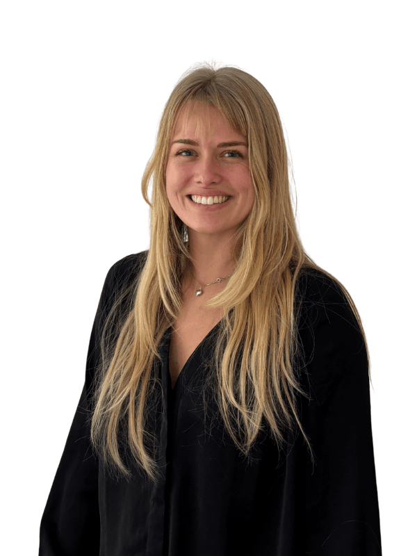 En ung kvinna med långt blont hår, mörk skjorta och ett smil, mot en vit bakgrund.
