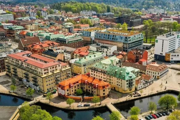 Färgglada byggnader i en stadlighet med kanaler och gröna träd, set från ovan.