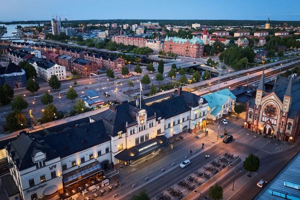 Flybild av en stad med kyrka, stadsbussstation, parkerade cyklar och vägar, med byggnader och gröna träd.