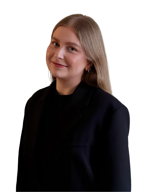 Ung kvinna med långt blont hår, ljus hud, och en svart kostym, ler mot kameran.